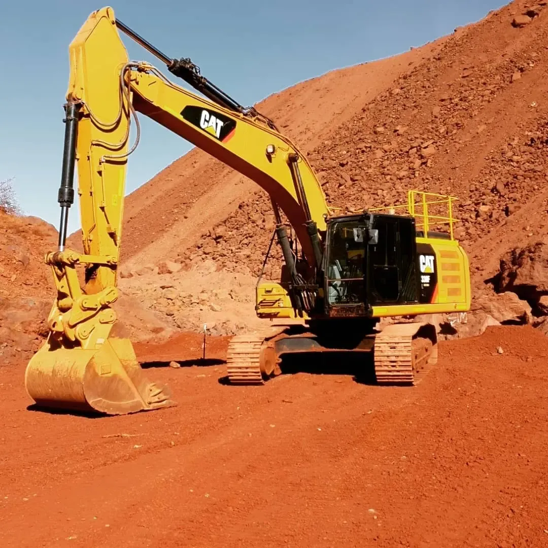 An excavator loading red clay on a steep bank